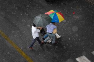 Uomini si riparano dalla pioggia in strada aprendo l'ombrello