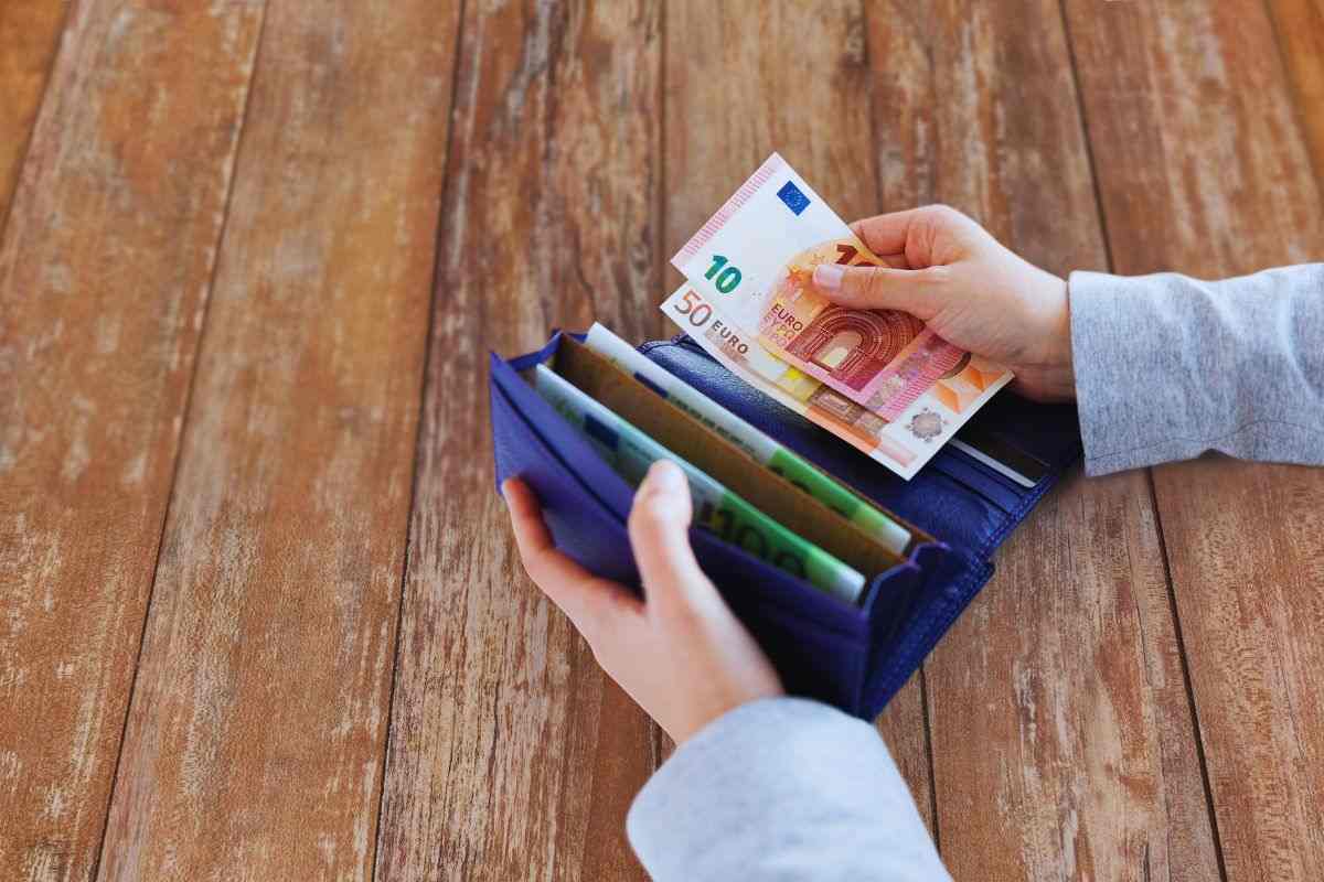 mani che mettono soldi in un portafoglio