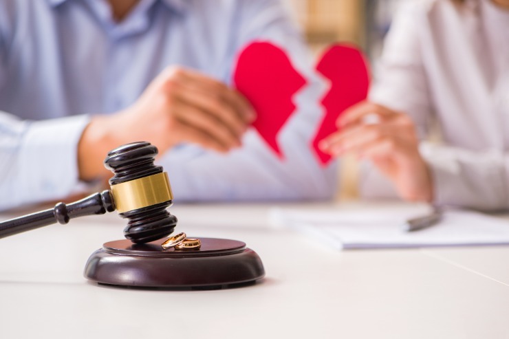cuore spezzato tra le mani di una coppia e in primo piano martelletto giudice