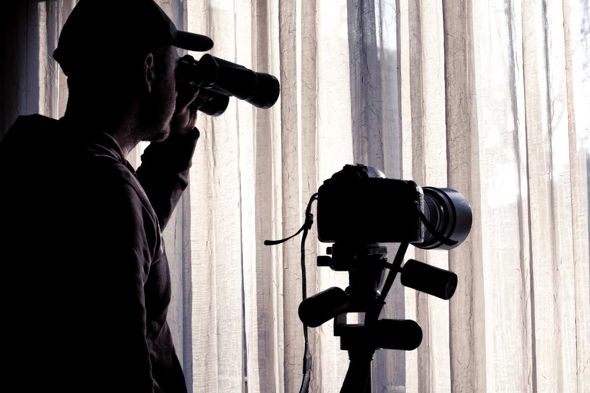 uomo spia con cannocchiale e videocamera