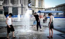 persone si rinfrescano con l'acqua di una fontana