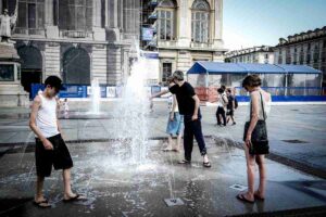 persone si rinfrescano con l'acqua di una fontana