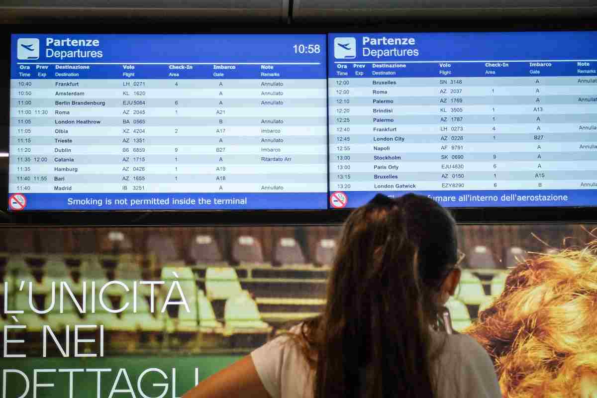 Gente in attesa sotto un tabellone aereo