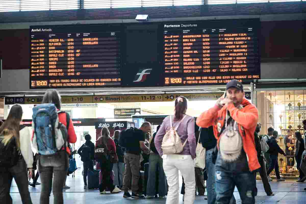 passeggeri guardano tabellone treni