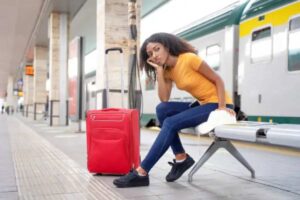 donna che aspetta con valigia in stazione