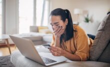 donna piange davanti a carta di credito e pc
