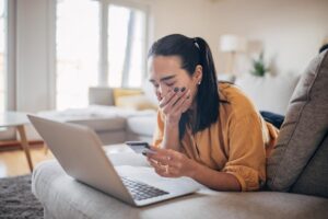 donna piange davanti a carta di credito e pc