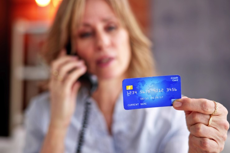 carta di credito in mano ad una donna sullo sfondo
