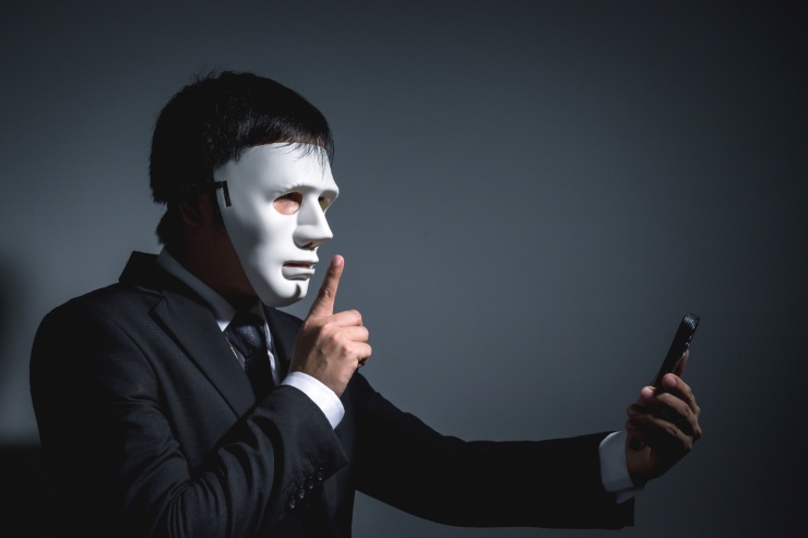 truffatore con maschera bianca al cellulare